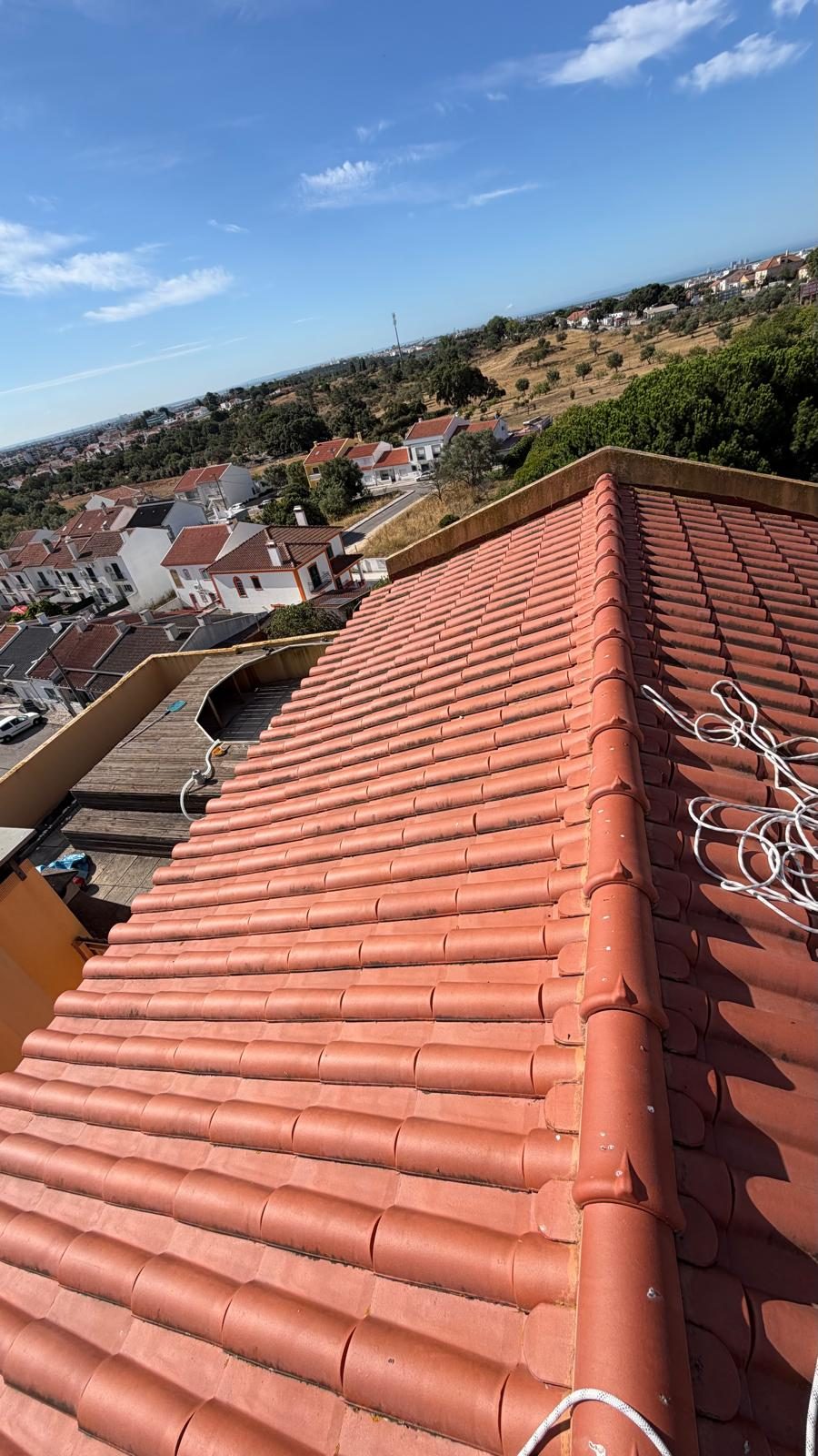 Cobertura de telha cerâmica lavada, vista ao longo da cumeeira sobre a vizinhança