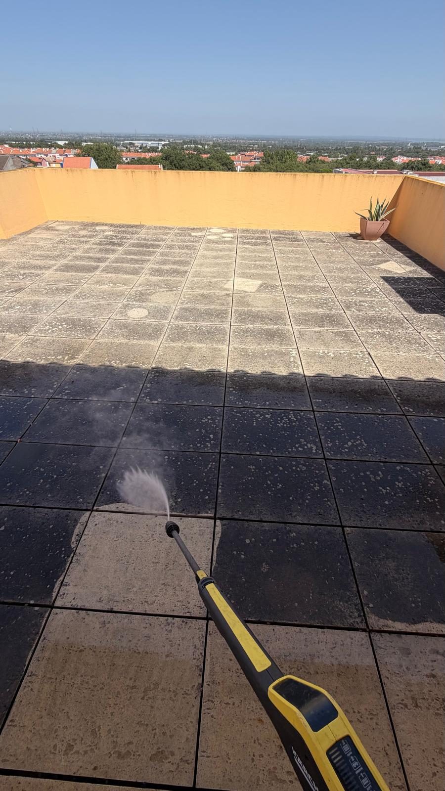 Lança de pressão a lavar a lajeta, com a zona já lavada clara encostada à zona por lavar, escura