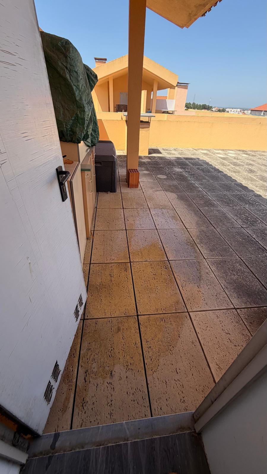Passagem coberta do terraço, com a lajeta lavada a encostar à parede do edifício